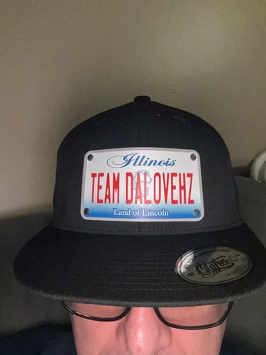 Reviewer wearing a black Illinois Plate Hat with a personalized license plate patch reading 'TEAM DALOVEHZ'.