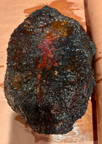 Customer's smoked USDA Prime Brisket with a dark, textured bark, resting on butcher paper.