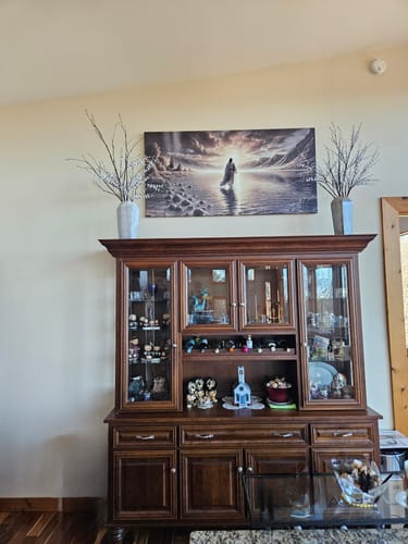 Customer's 'Walking On Water - Faith' canvas hanging in their home above a dark wood china cabinet.