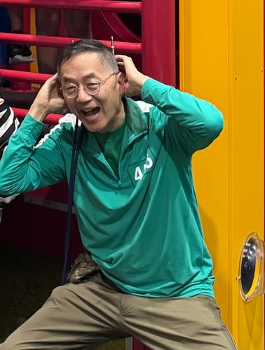 A happy customer wearing the green Squid Game '456' – Quarter Zip at a child's birthday party.