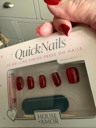 Reviewer holding the packaging for Cranberry Crush press-on nails, showing the red, square nails inside.