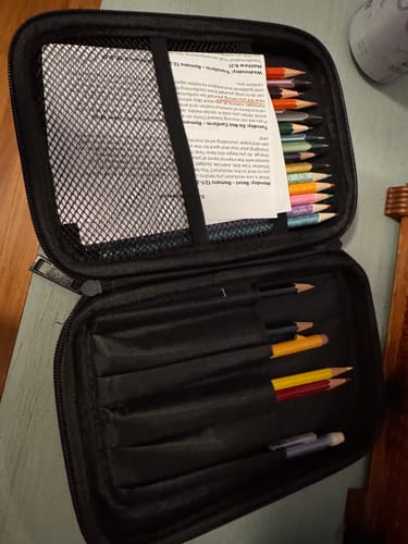 Customer's open hard shell pencil case showing colored pencils organized in its multiple compartments and mesh pocket.
