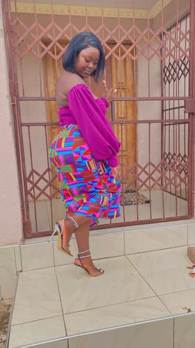 Reviewer shows a side view of the High Waisted Skirt and Corset Top Set, with a magenta top and multicolored skirt.