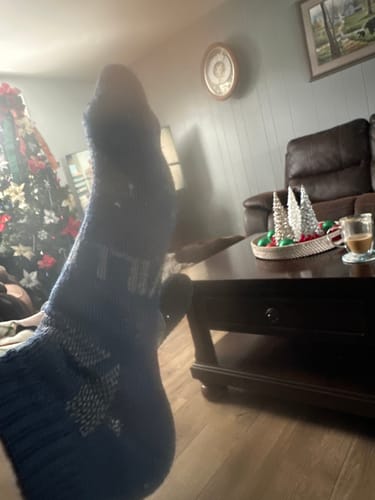 Customer shows a close-up of their blue patterned Men's Alpaca Sock while relaxing at home.