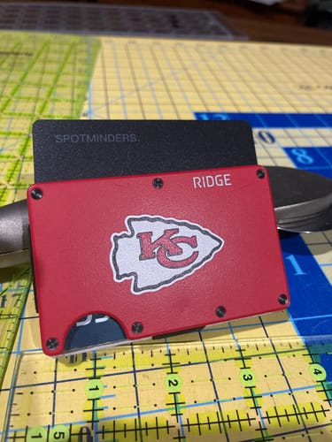 Reviewer's black SPOTMINDERS tracking card shown partially inserted into a slim red wallet on a work surface.