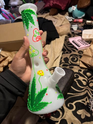 Customer holding the white glass bong with its colorful hemp leaf and shroom designs.