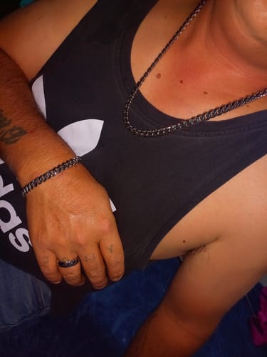 Cliente mostrando la Cadena Cuban de 10 mm y una pulsera a juego con una camiseta de tirantes negra.
