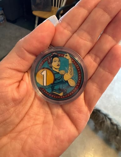 Reviewer holding the round Rosie Recovery 1 Year Medallion in their palm.