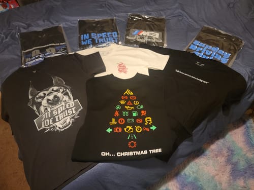 Customer's assortment of graphic T-shirts from the TCG89 Mystery Cash Box displayed on a bed.