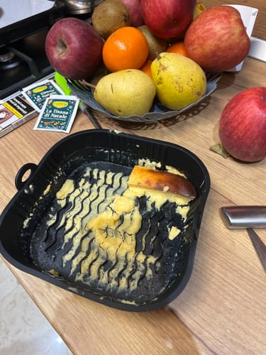 Imagine de la un client cu cuva air fryer-ului Novio StonePro pe o masă, cu resturi de mâncare după gătire.