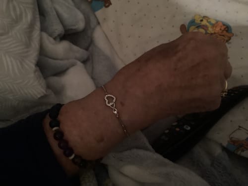 Close-up of a reviewer's wrist wearing a silver-colored bracelet with an intertwined heart design.