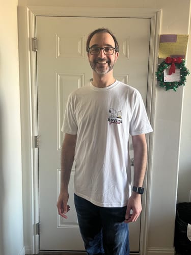 Reviewer smiling while wearing the white Peanuts "Sailin' Away" tee, showing the fit and front logo.