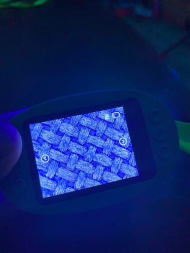 Nahaufnahme des Bildschirms des Abenteuer-Mikroskops eines Kunden, der eine stark vergrößerte blaue Gewebestruktur zeigt.