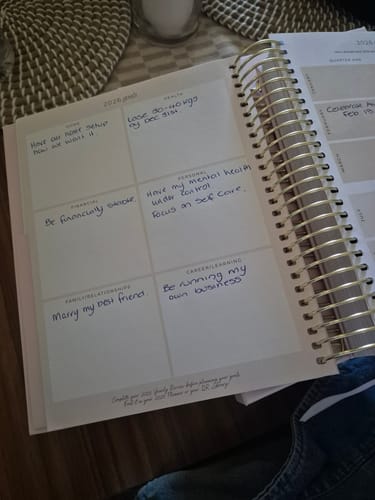 Reviewer's 2026 Signature Planner open to the '2026 goals' page, filled with handwritten goals and showing the gold spiral binding.