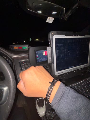 Close-up of a customer's wrist wearing the FIDES Cross Leather & Bead Bracelet in a vehicle.