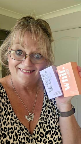 Reviewer smiling while holding the packaging for Fleur Mystique and another fragrance from the same brand.