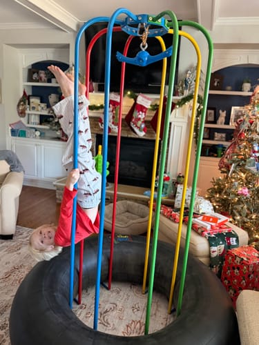 Customer's child hanging upside down from the colorful bars of a Jungle Jumparoo indoors.