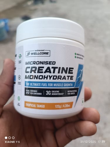 Customer holds the white tub of Wellcore Micronised Creatine Monohydrate in Tropical Tango flavor.