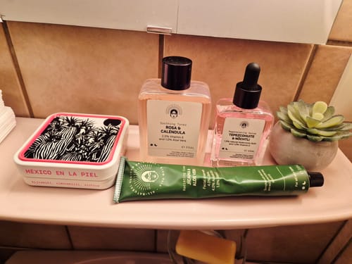 Reviewer's Barrier Protection Routine products, including a toner and serum, arranged on a pink bathroom shelf.