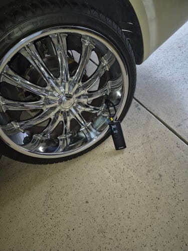 Customer's Airmoto connected to a car tire with a shiny chrome rim inside a garage.