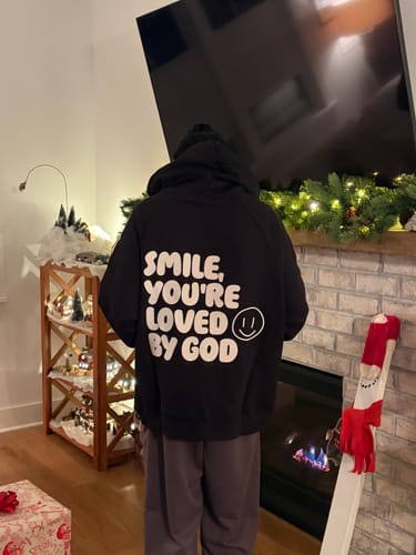 Customer from behind wearing a black sweatshirt with "SMILE, YOU'RE LOVED BY GOD" printed on the back.