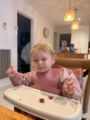 Customer's baby using the Paloma baby chair v2 as a booster seat with its tray at a dining table.