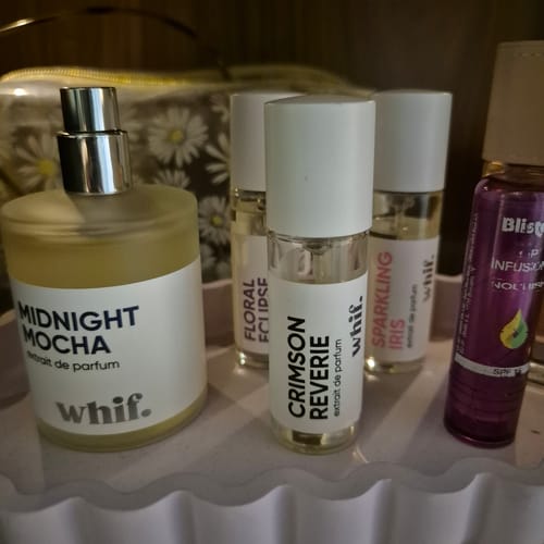 Reviewer's small bottle of Crimson Reverie perfume sits on a tray with other fragrance bottles.