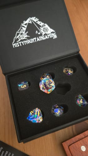 Customer's multifaceted Diamond Prism Glass Dice Set displayed in its open black box, showing an iridescent finish.