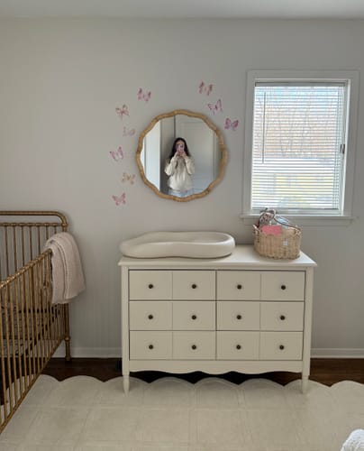 Customer's nursery showing the soft pink butterflies decal set on the wall above a white dresser and around a mirror.