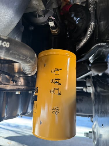 Customer's close-up of the SPE Motorsport Oil Filter Housing installed with a yellow CAT filter in an engine bay.