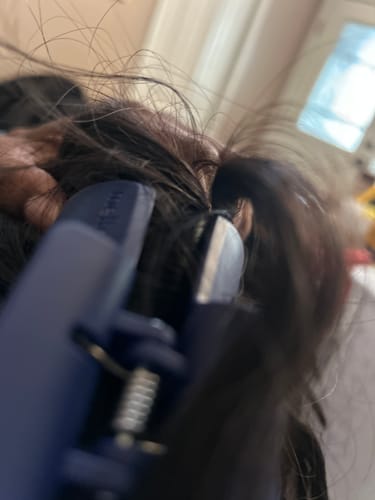 Close-up of a customer's dark blue cloud clip holding up their thick, dark hair.