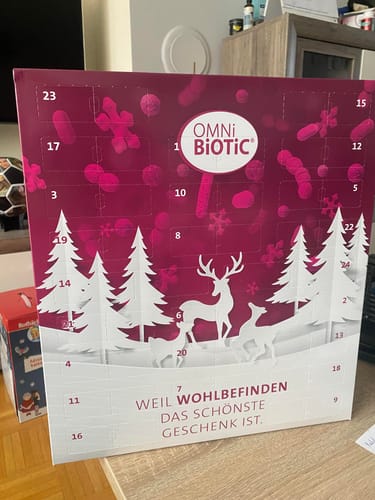 Kundenfoto des magenta-weißen OMNi-BiOTiC Adventskalenders mit Wintermotiv, der auf einem Tisch steht.