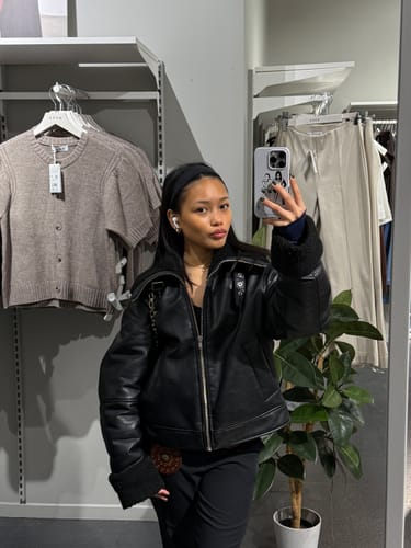 Reviewer taking a mirror selfie in a store with their after party tough iPhone case.