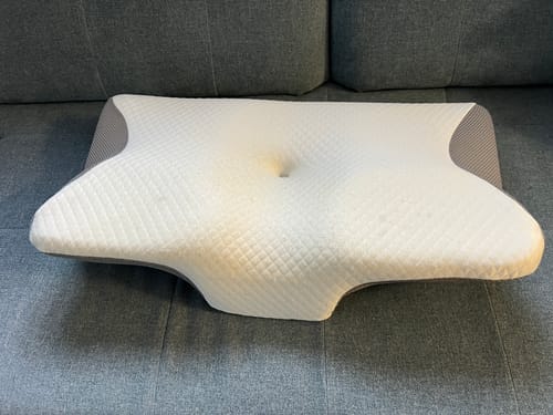 Vásárló ergonomikus anatómiai párnája egy szürke kanapén.
