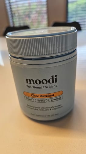 Customer's light blue tub of moodi Choc Hazelnut Functional PM Blend on a white surface.