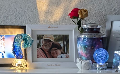 Reviewer's two Lucite Light Stands illuminating glass art pieces on a shelf next to a photo and an urn.