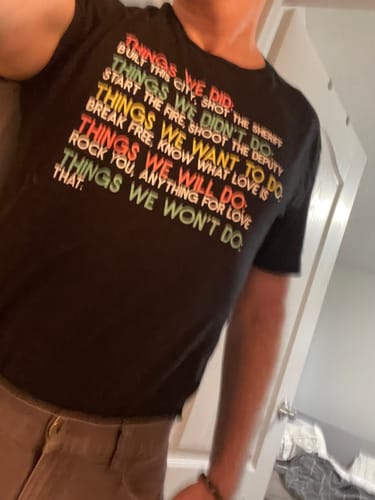 Partial view of a customer wearing the black 'Things We Did T-Shirt', showing the fit and colorful text.