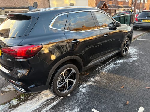 Customer's shiny black car after a wash, with foam from the Build A Bundle products still on the ground.