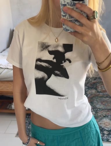 Customer's mirror selfie showing the fit of the white love or lust baby tee with its black graphic.