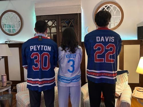Customer showing the backs of three people wearing their personalized blue and white hockey jerseys.