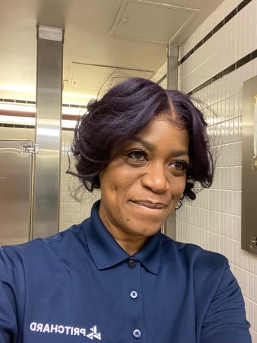 Reviewer wearing the wavy Outre Kinkysoft 2 wig, showing its dark purple color and soft texture in a selfie.