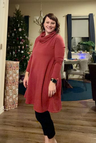 Reviewer smiling while wearing the red Cowl Neck Swing Dress with leggings in a living room.