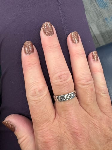 Customer's hand wearing the engraved Mountains & Forests Ring on their ring finger.