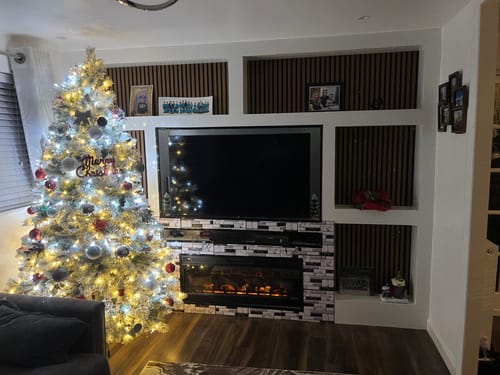 Customer's dark wood slatted wall panels installed as an accent within a white entertainment center in a living room.