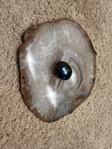 Customer's dark Labradorite Moonstone with a blue glow, resting on a polished agate slice.