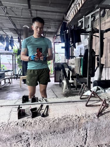 Customer taking a selfie in a gym while wearing the blue AQ Classic Fitness Gloves.