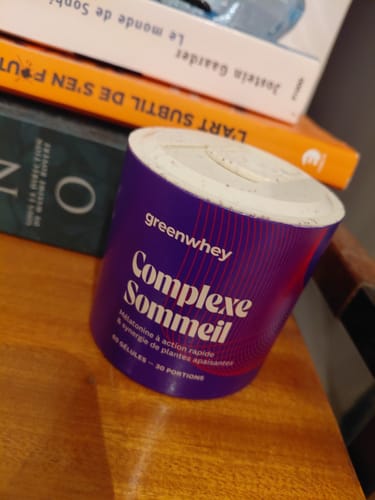 Le pot violet de Complexe Sommeil d'un client sur une table en bois, à côté de quelques livres.