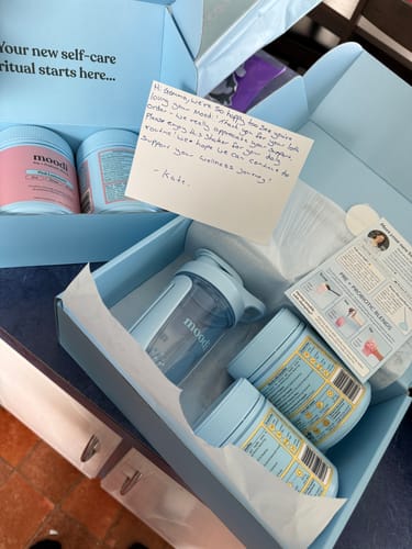 Customer's Original Pre + Probiotic Bundle unboxed, showing tubs of powder, a shaker, and a note inside two blue boxes.