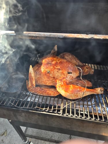 Reviewer smoking a seasoned, spatchcocked turkey on a grill, prepared with the Turkey Brine Kit.