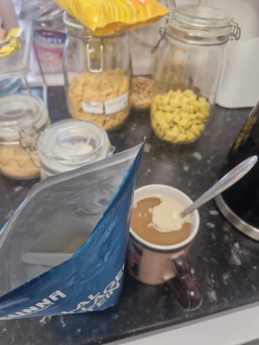 Customer stirring their Collagen supplement into a beverage in a bronze mug, with the open pouch next to it.